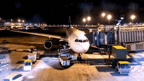 Cargo aircraft being loaded at an airport gate at night
